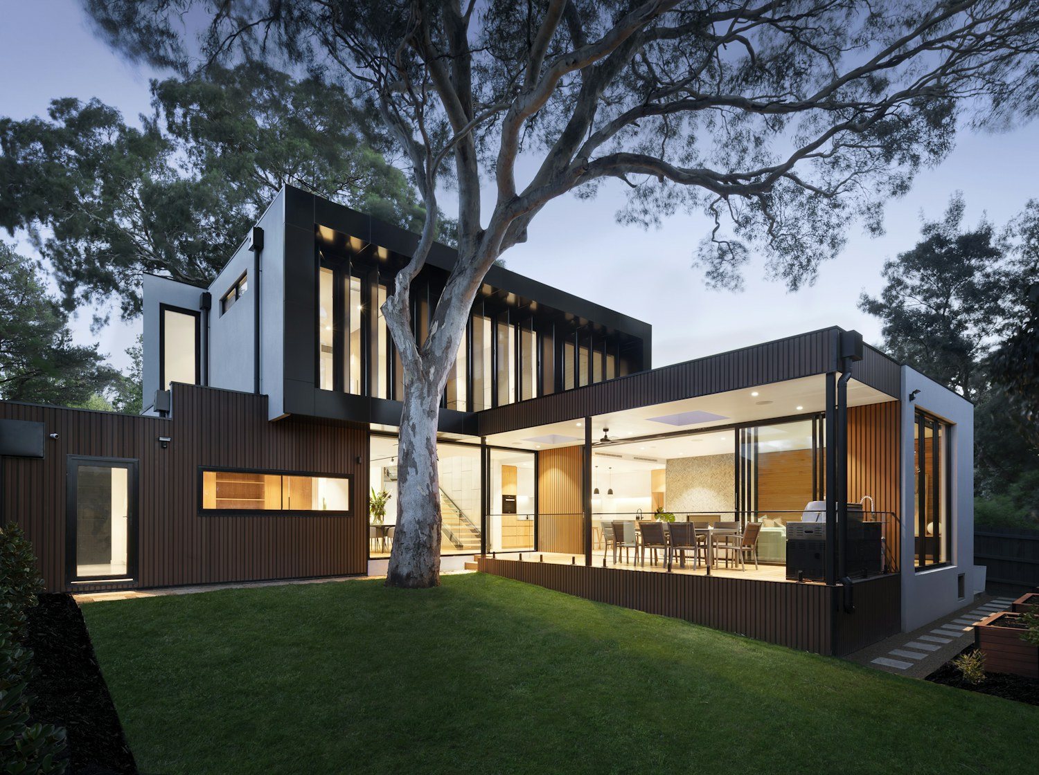 Contemporary renovated home surrounded by trees at dusk